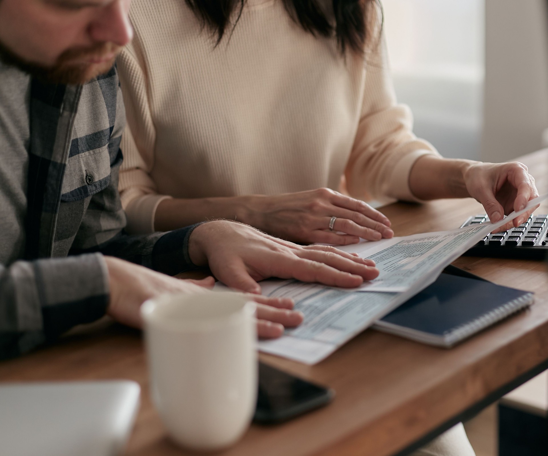 A couple reviewing contractor estimates together at a kitchen table with a calculator.